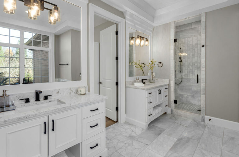 A contemporary bathroom with marble flooring, a double vanity area, and a set of warm pendant lights