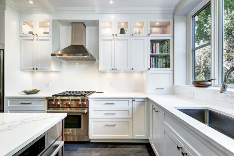 A kitchen interior with exhaust hood, a stove range, oven, sink, and hanging cabinet with built in LED lights