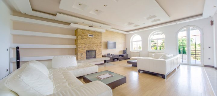 A huge family room with fireplace, an entertainment set. a wide set of white couch on both sides of the room