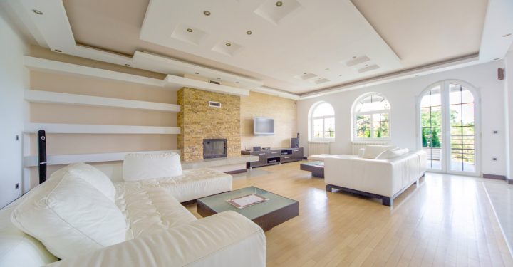 A huge family room with fireplace, an entertainment set. a wide set of white couch on both sides of the room