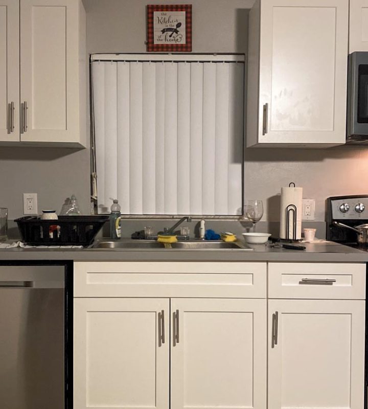 A Kitchen Sink with marble countertop. a stove oven. cabinets and a window with blinds