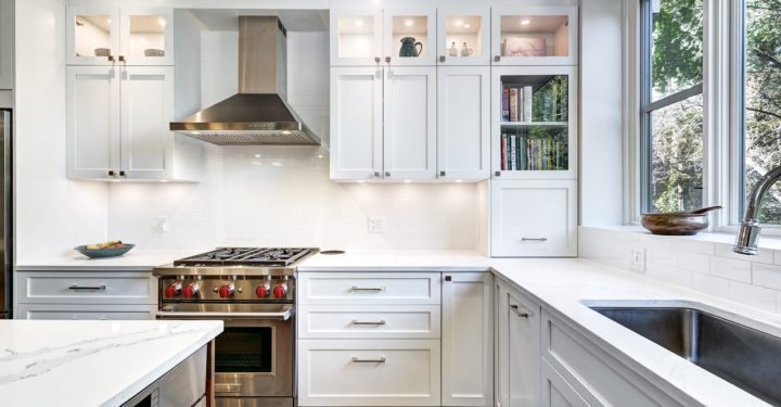 A kitchen interior with exhaust hood, a stove range, oven, sink, and hanging cabinet with built in LED lights